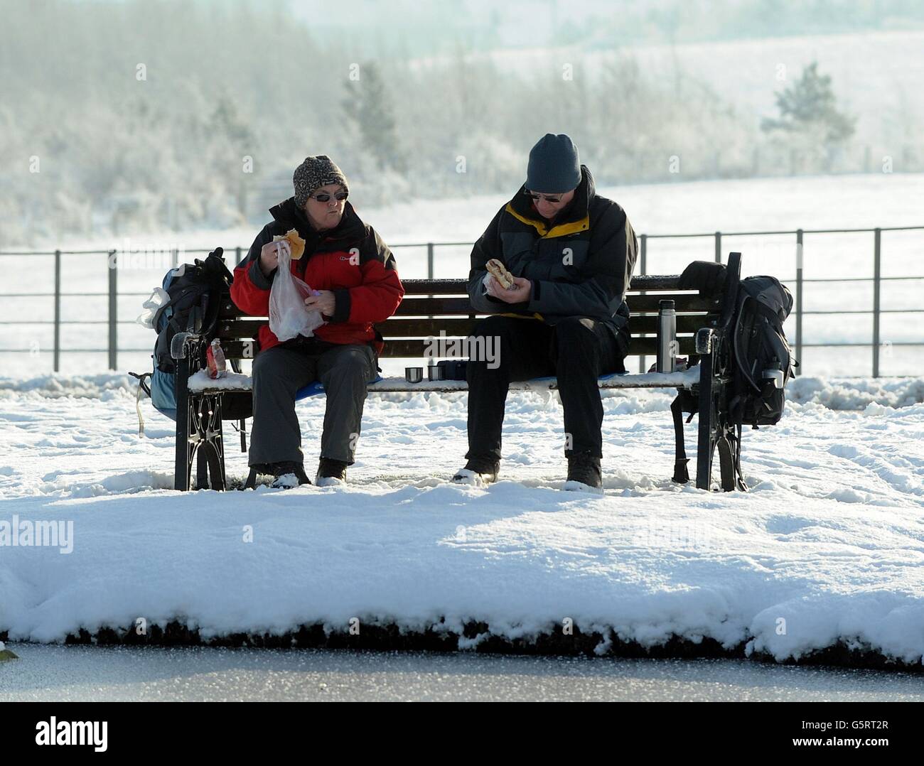 Zwei Personen genießen ihr Mittagessen an einem gefrorenen See im Herrington Country Park in der Nähe von Sunderland. Stockfoto