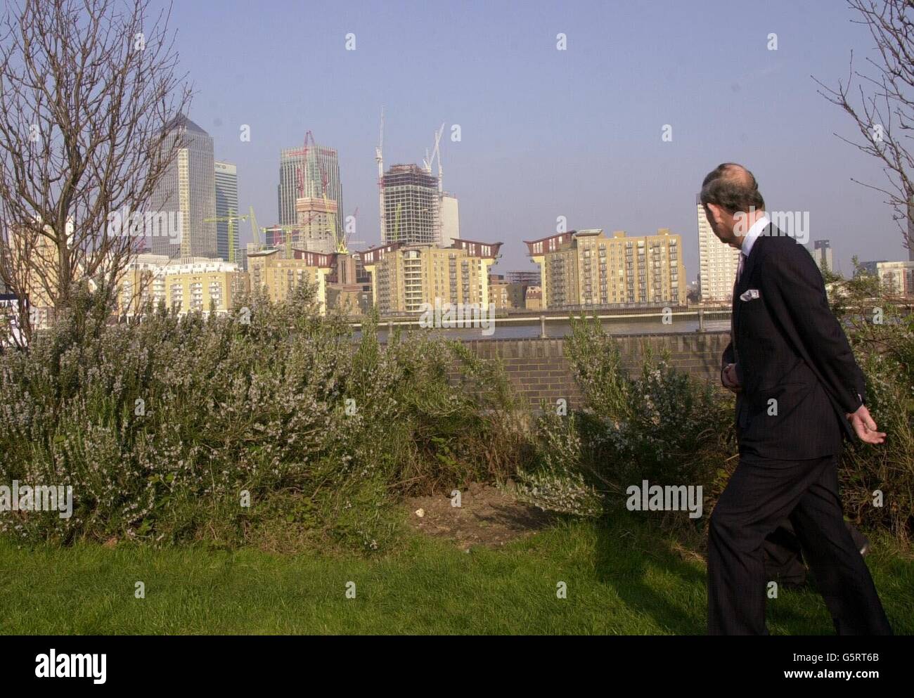 Der Prinz von Wales blickt auf die Canary Wharf Entwicklungen, hinter, während eines Besuchs der Surrey Docks City Farm, South East London. Stockfoto