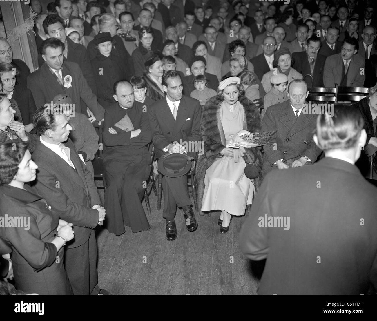 Das Verlobte Ehepaar, Prinzessin Margarita von Baden und Prinz Tomislav von Jugoslawien, saß bei der offiziellen Verlobungszeremonie in der Serbisch-Orthodoxen Kirche in Notting Hill, London, zwischen Pfarrer M. Nikolitch, links, und Prinz Wolfgang von Hessen. Prinzessin Margarita, Nichte des Herzogs von Edinburgh und Tochter des markgraf und Markgraffin von Baden, ist Krankenschwester am St. Thomas's Hospital in London. Prinz Tomislav, der in Sussex landet, ist der Sohn der Königin Marie von Jugoslawien und des verstorbenen Königs Alexander. Stockfoto