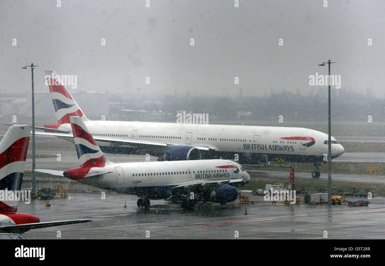 Flugzeuge manövrieren in einem Schneeschauer am Flughafen Heathrow, während das Winterwetter in ganz Großbritannien anhält. Stockfoto