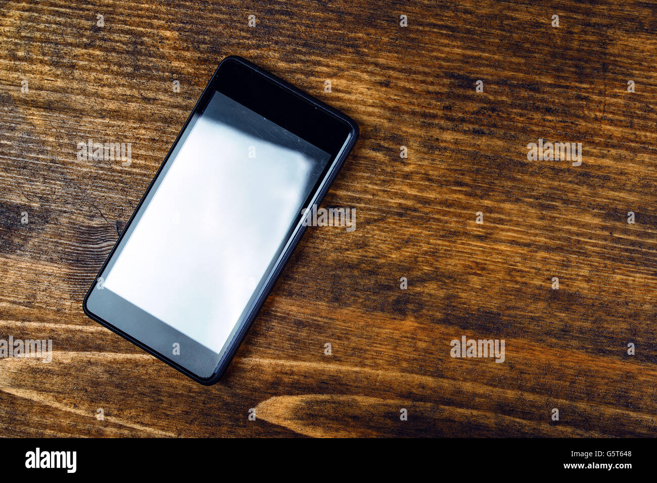 Gebrauchte smart Phone auf hölzernen Schreibtisch legen leerer Bildschirm als Textfreiraum, flache Draufsicht Stockfoto