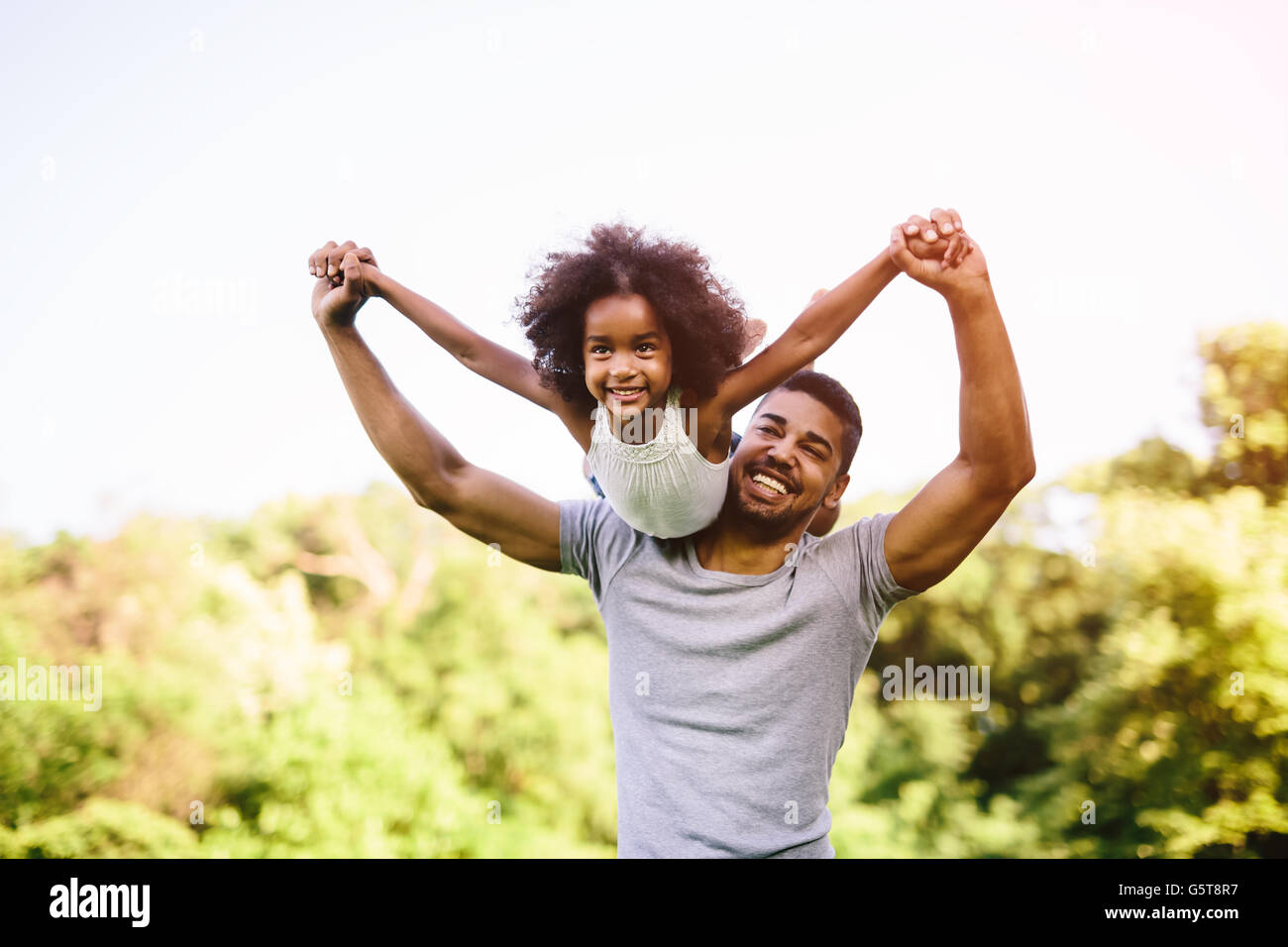 Kind auf Vaters Schultern während Huckepack statt fliegen Stockfoto