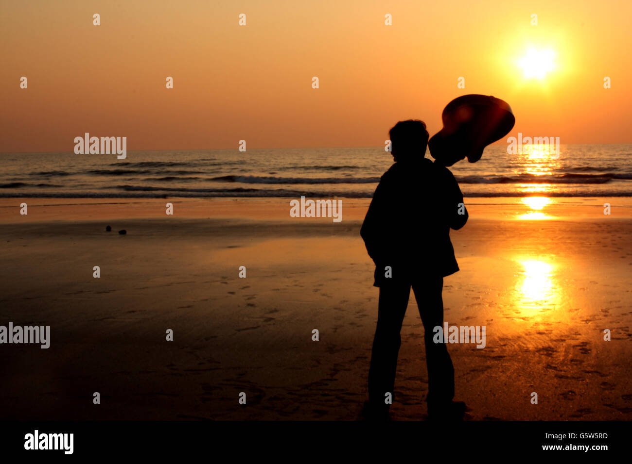 Eine Silhouette eines einsamen Gitarristen an einem Strand. Stockfoto