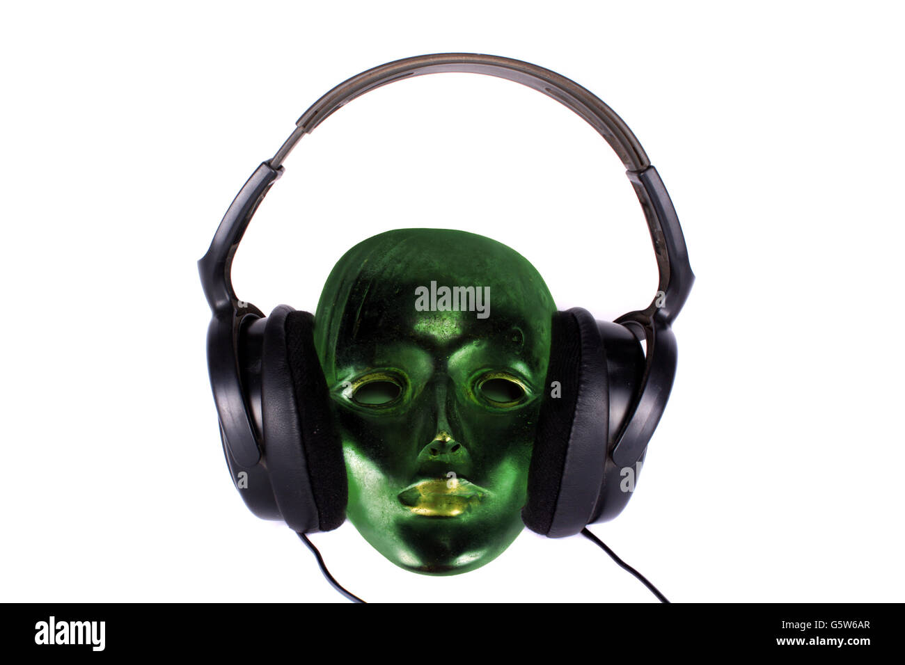 Eine antike grüne Maske hören von Musik über Kopfhörer. Stockfoto