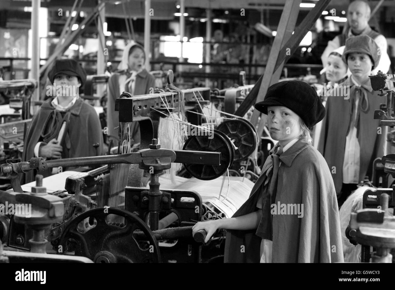 FARBBILDER WERDEN IN SCHWARZWEISS KONVERTIERT. Kinder der Style Primary School Teil des Quarry Bank Mill Estate reinagieren eine Belegschaft in der Quarry Bank Mill, die dem National Trust gehört. Stockfoto