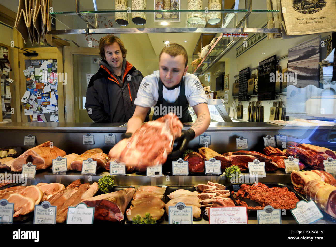 Metzger Paul Gyorgy greift für einen Kunden im Sheeptrieb Organic Farm Shop in Bristol nach einem Stück Fleisch. Stockfoto