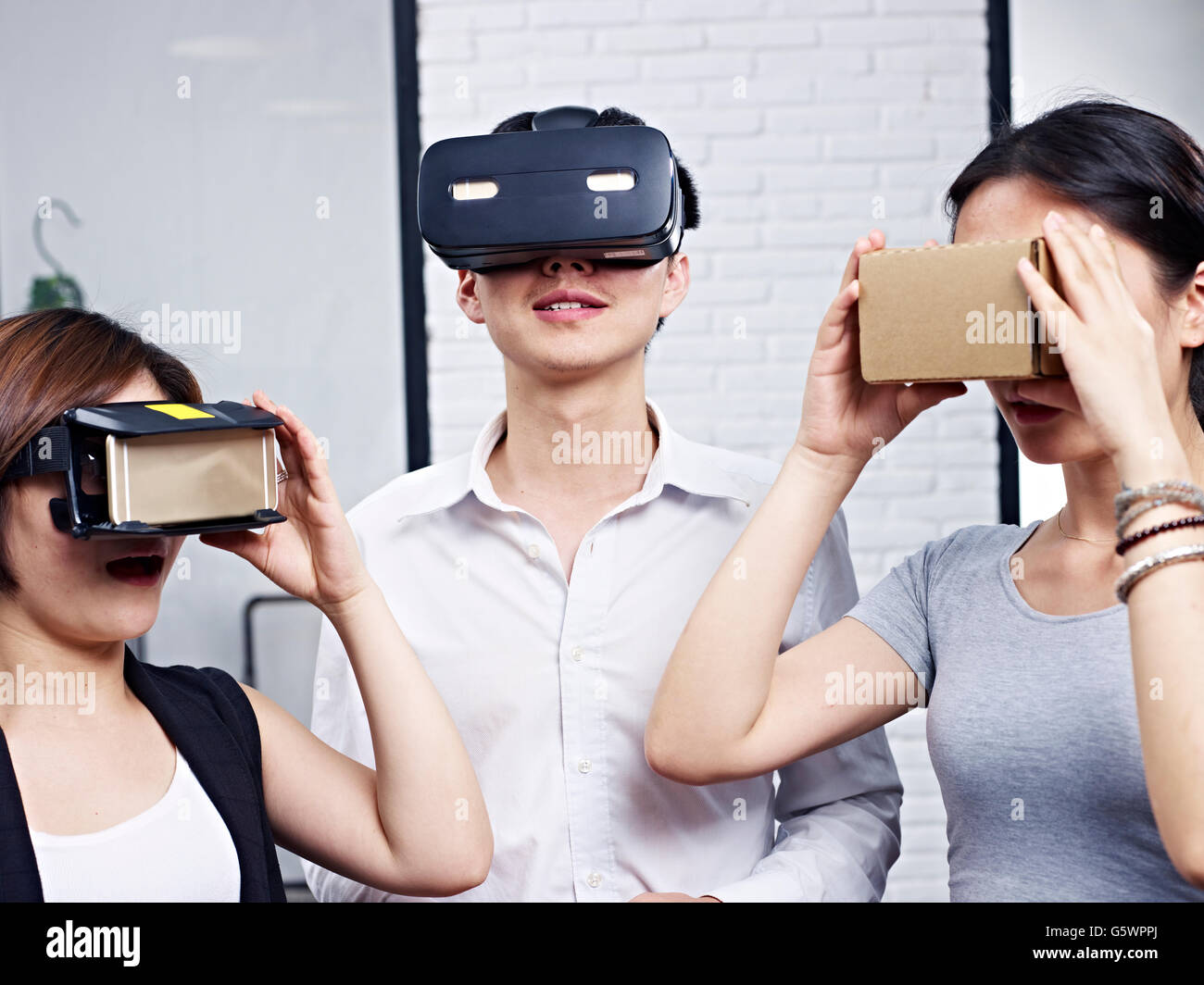 drei junge Asiaten tragen verschiedene Arten von virtueller Realität (VR) Brille. Stockfoto