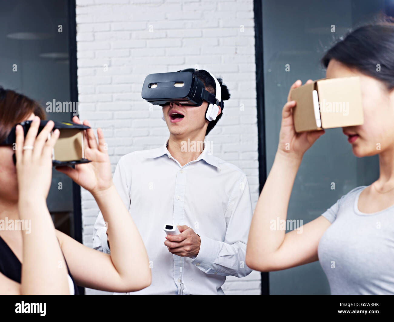 drei junge Asiaten tragen verschiedene Arten von virtueller Realität (VR) Brille. Stockfoto