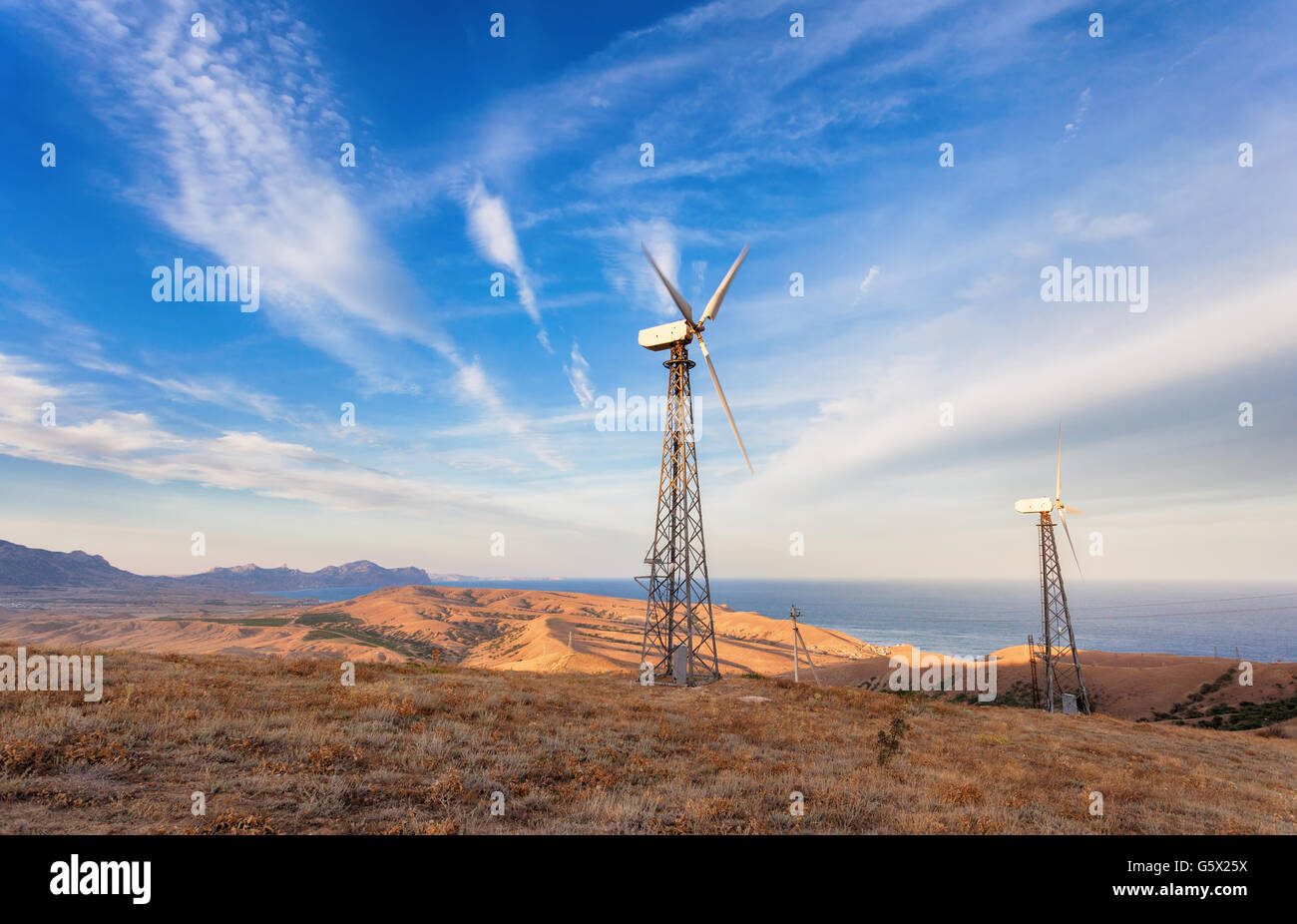 Industrielandschaft mit Windkraftanlage zur Stromerzeugung in Berge bei Sonnenuntergang. Stockfoto