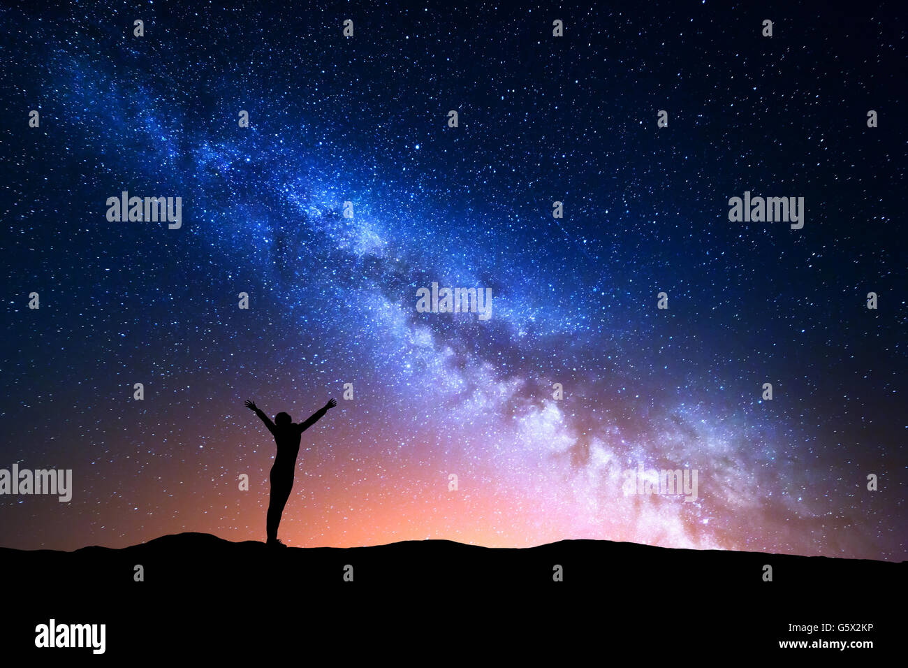 Landschaft mit blauen Milchstraße und gelbes Licht. Bunte Nachthimmel mit Sternen und Silhouette eines stehenden sportlichen Mädchens mit rais Stockfoto