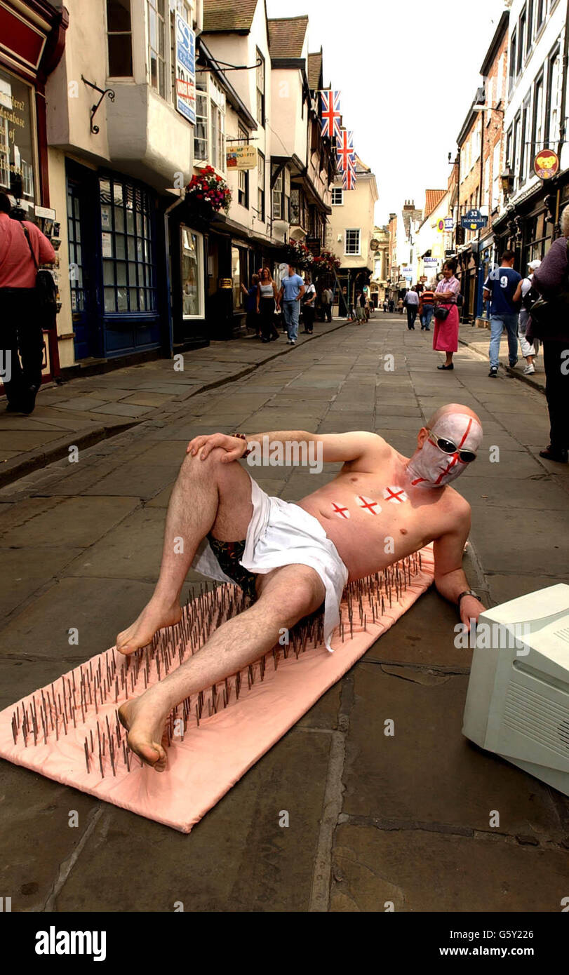 England Fußball-Fan Michael MIME aus York bereitet sich darauf vor, das Finale des WM-Quartals zwischen England und Brasilien am Freitag von einer ungewöhnlichen Position aus zu sehen. * Er hat sein eigenes Nagelbett aus 1050 Nägeln, die er in einem lokalen Baumarkt gekauft hat, hergestellt und wird auf den Nägeln in der Straße in York liegen und das Spiel auf einem tragbaren Fernseher ansehen. Michael sagte, er habe so viel gelitten, dass er an die Idee nach dem Spiel in Dänemark dachte und zu seiner Überraschung fand, dass er den Schmerz ertragen konnte. Stockfoto