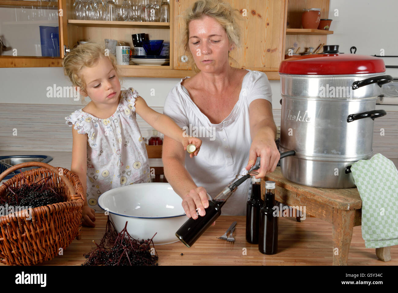 Frau und Mädchen Kochen Holunder Saft Holunder, Holunder / (Sambucus Nigra, Ort Fructus) Stockfoto