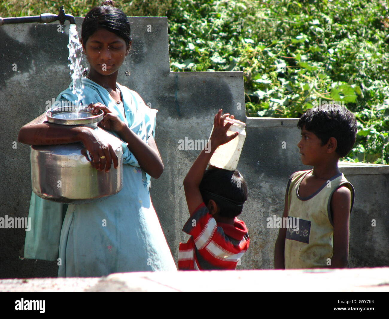 Eine Frau und jungen füllen Wasser in ihren Behältern während einer Dürre in Indien Stockfoto