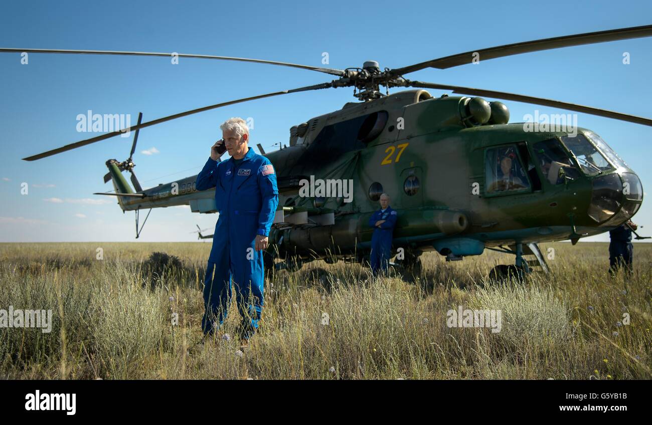 NASA Fliegerarzt Rainer Effenhauser verwendet ein Satellitentelefon melden den Status der NASA-Astronaut Tim Kopra aus außerhalb der russische MI8 Hubschrauber kurz nach Kopra, ESA-Astronaut Tim Peake und russischen Kosmonauten Yuri Malenchenko landete an Bord der russischen Sojus TMA-19 M Sonde 18. Juni 2016 in der Nähe von Zhezkazgan, Kasachstan. Stockfoto