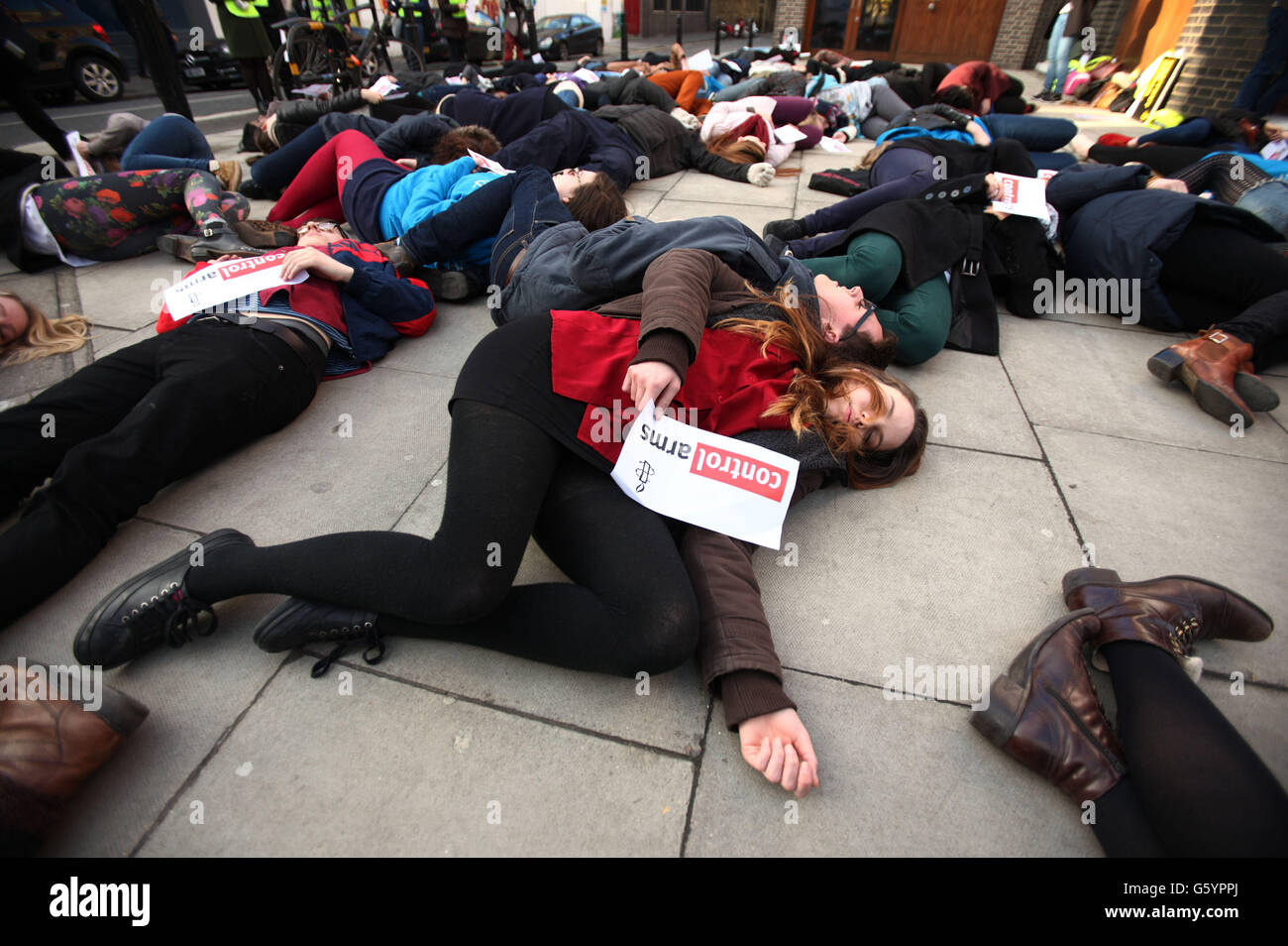 Studenten aus ganz Großbritannien liegen während eines „Einmarsch“-Protests von Amnesty International vor Ort, um die Auswirkungen des schlecht regulierten Waffenhandels im Amnesty International Human Rights Action Center im Zentrum von London zu veranschaulichen. Stockfoto
