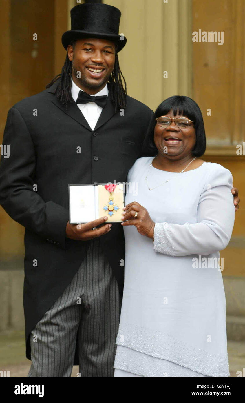 Der Schwergewicht-Boxweltmeister Lennox Lewis hält zusammen mit seiner Mutter Violet seine Commander of the British Empire-Medaille (CBE), die ihm der Prinz von Wales im Buckingham Palace überreichte. Stockfoto