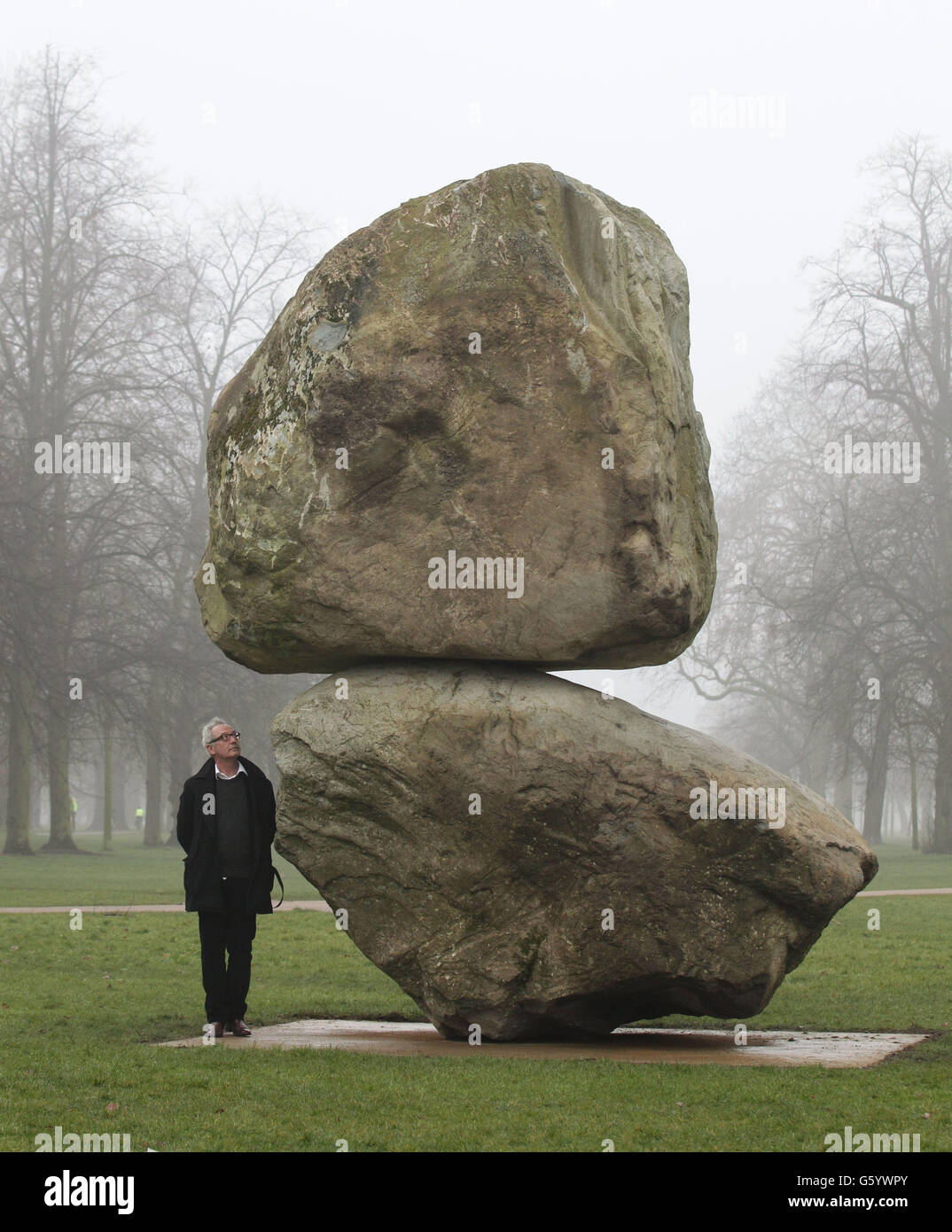 Der Künstler Peter Fischli steht neben seiner großformatigen Boulderskulptur 'Rock on Top of Another Rock', die das Künstlerduo Fischli/Weiss bei der Enthüllung in der Serpentine Gallery im Hyde Park, London, gezeigt hat. Stockfoto