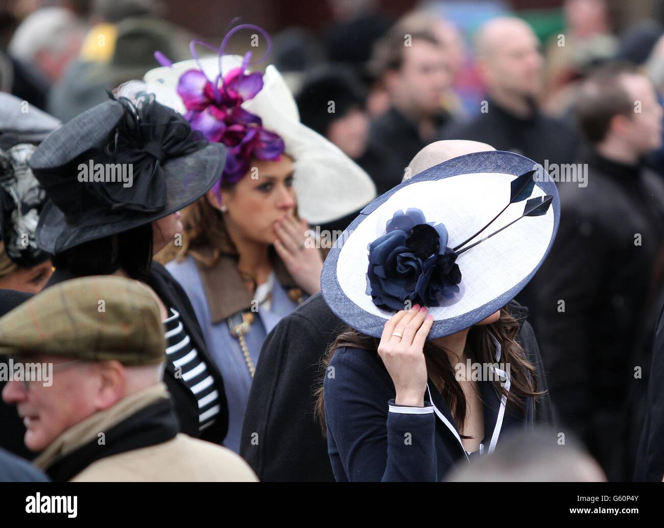 Pferderennen - 2013 Cheltenham Festival - Tag Vier - Cheltenham Rennbahn. Eine Rennfahrerin hält sich am Cheltenham Gold Cup Day während des Cheltenham Festivals an ihren Hut. Stockfoto