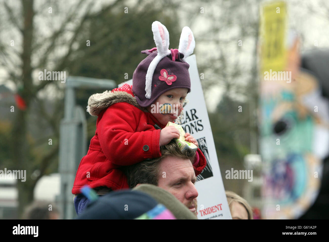 Ein Kind sitzt auf den Schultern eines Mannes, während Anti-Atom-Demonstranten an einer Demonstration teilnehmen, die von der Kampagne für nukleare Abrüstung (CND) organisiert wird, am Hauptsitz des Atomwaffenbetriebs in Aldermaston, in der Grafschaft Bekshire. Stockfoto