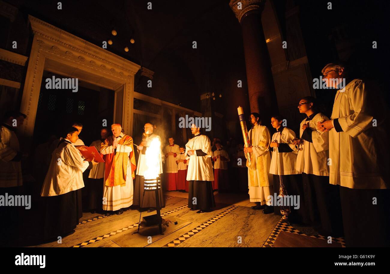Klerus zünden die Osterkerze während der Ostermesse an, in der Westminster Cathedral, im Zentrum von London. Stockfoto