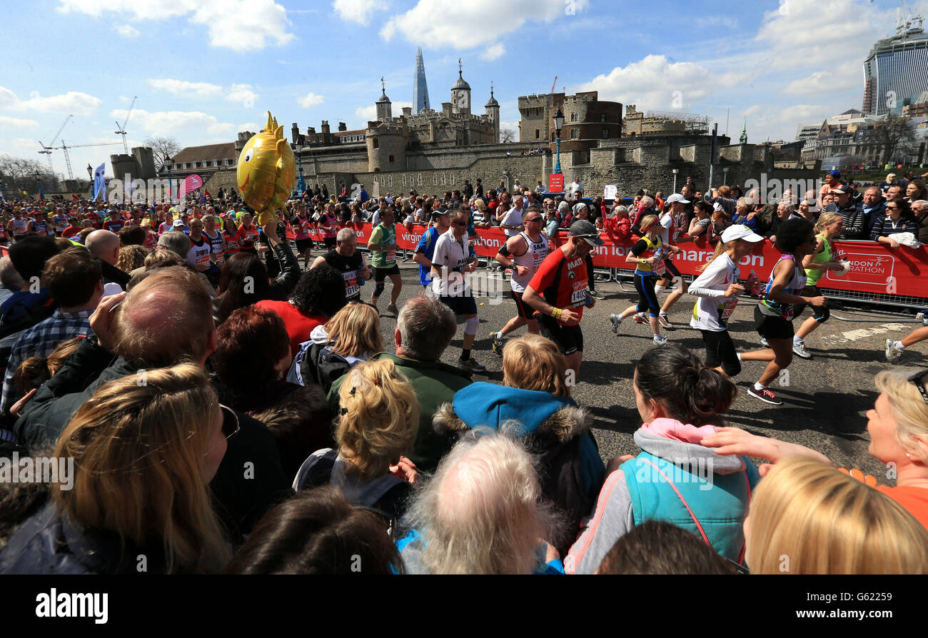 Die Zuschauer feuern die Läufer an, während sie am Tower of London beim Virgin London Marathon in London vorbeifahren. Stockfoto