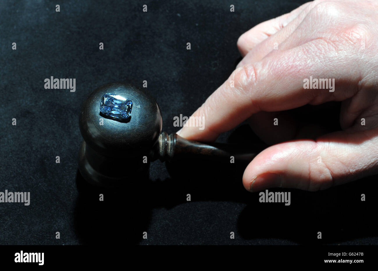 Ein Mitarbeiter von Bonham's Auctioneers im Zentrum von London platziert einen 5.3 Karat schicken blauen Diamanten auf einen Auktionatoren-Gavel. Stockfoto