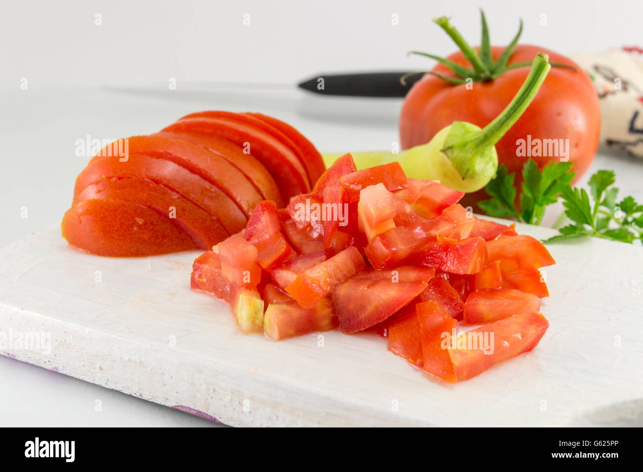 Frische Tomatenscheiben auf einem weißen Holzbrett Stockfoto