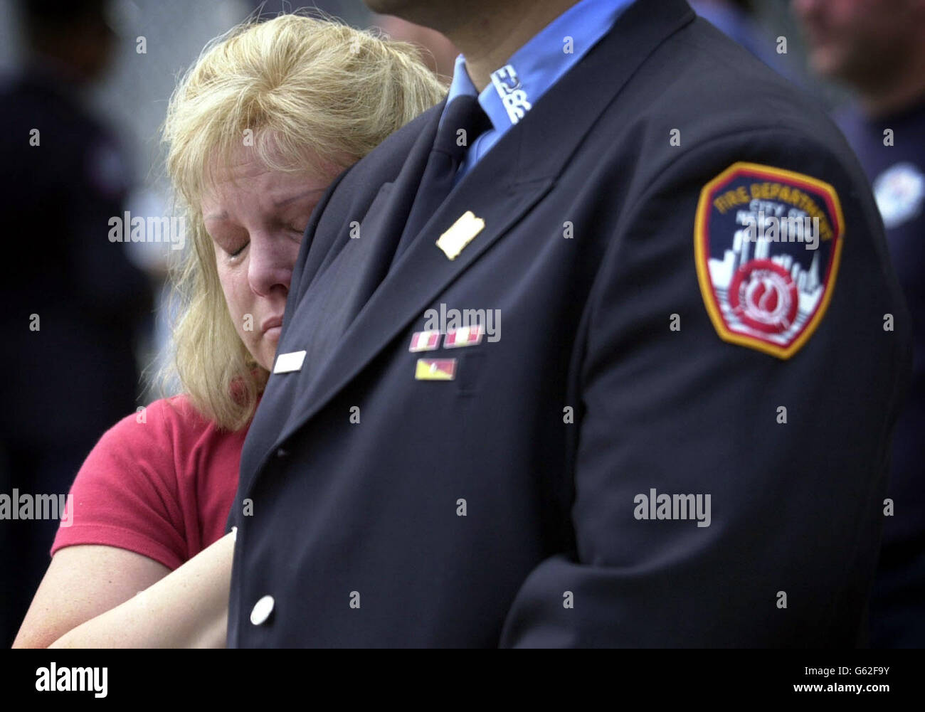 Eine Dame hängt an ihrem Mann, einem New Yorker Feuerwehrmann, der zum ersten Jahrestag der Terroranschläge auf das World Trade Center anwesend ist. Stockfoto