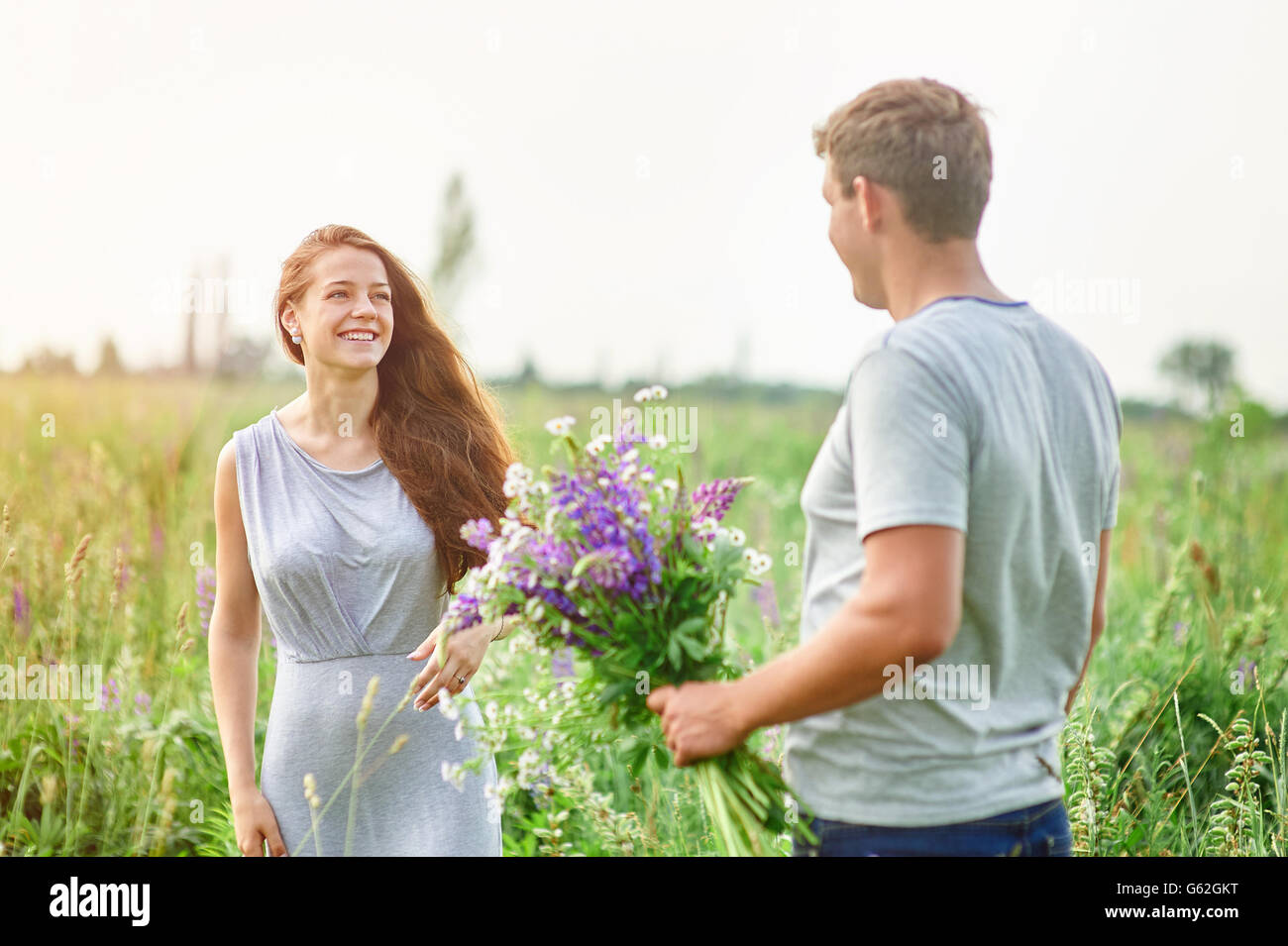 glückliches Paar spielen mit einander in einem Feld Bouquet von Lupinen Stockfoto