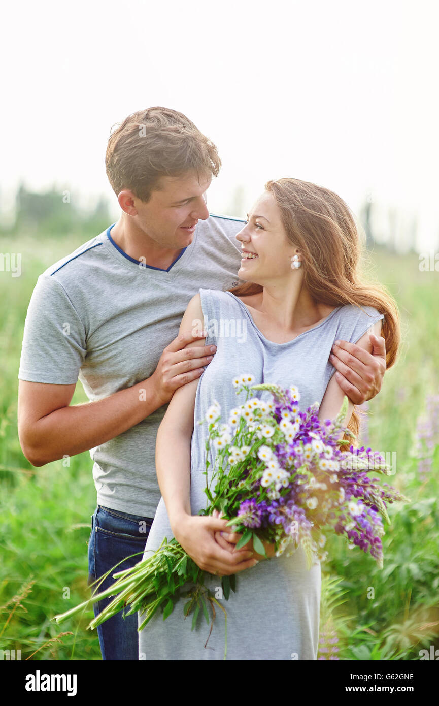 glückliches Paar spielen mit einander in einem Feld Bouquet von Lupinen Stockfoto