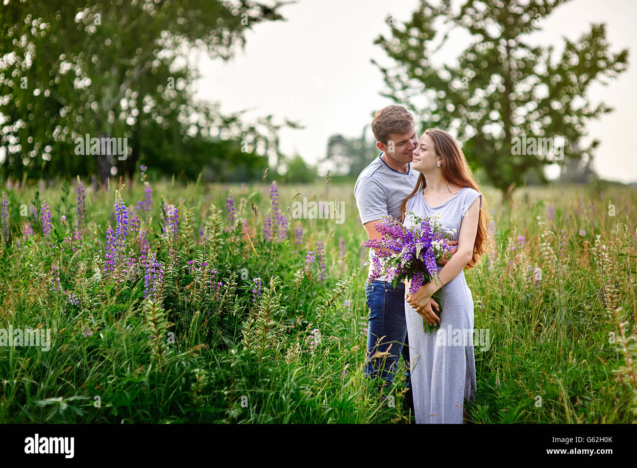 schöne Frau mit langen Haaren und ein glücklicher Mann umarmt im Feld Stockfoto