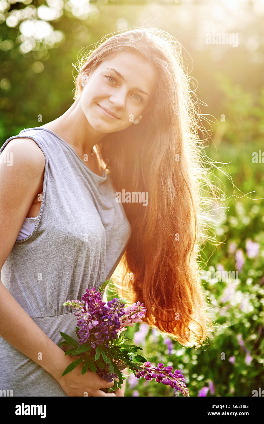 Lächelnd junges Mädchen hält einen Blumenstrauß lupine auf sonnigen Sommerwiese Stockfoto