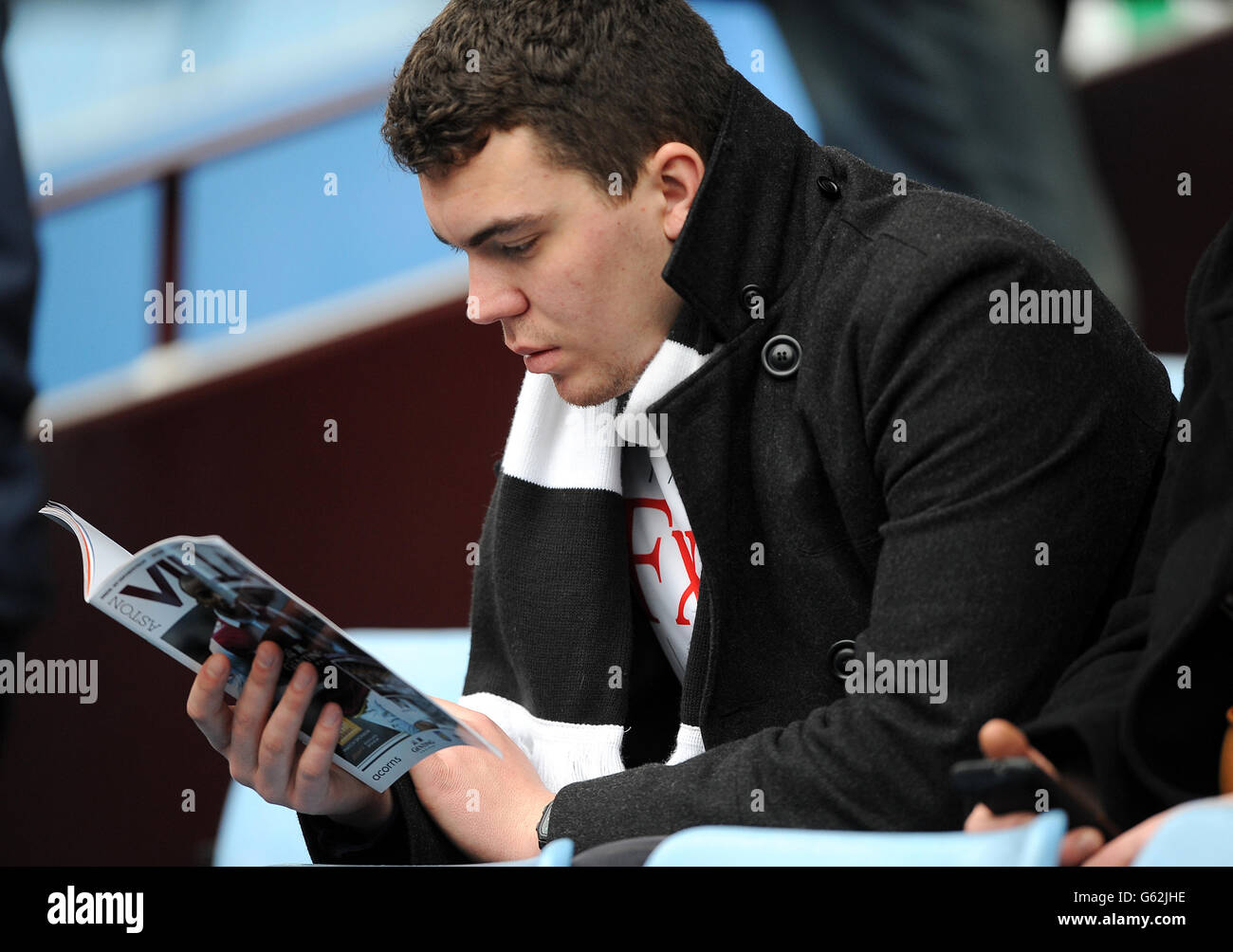 Ein Fulham-Fan liest das Match Day-Programm auf den Tribünen Stockfoto