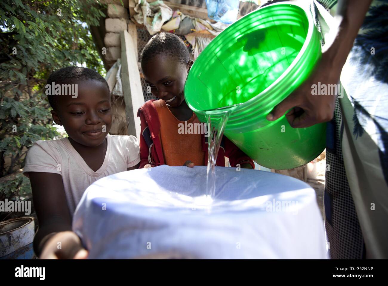 Kinder aus einem Dorf in Tansania, Afrika, mischen sich in einem Beutel mit Procter and Gamble's (P&G) Purifier of Water Purify Technologie, die von P&G Wissenschaftlern entwickelt wurde, um die Krise des sauberen Trinkwassers weltweit zu bekämpfen. P&G hat sich mit Asda für eine Kampagne für sauberes Wasser zusammengetan, die dazu beitragen soll, ein Leben pro Stunde durch ein 1-Pack = 1 Tag sauberes Trinkwasser-Programm zu retten. Stockfoto