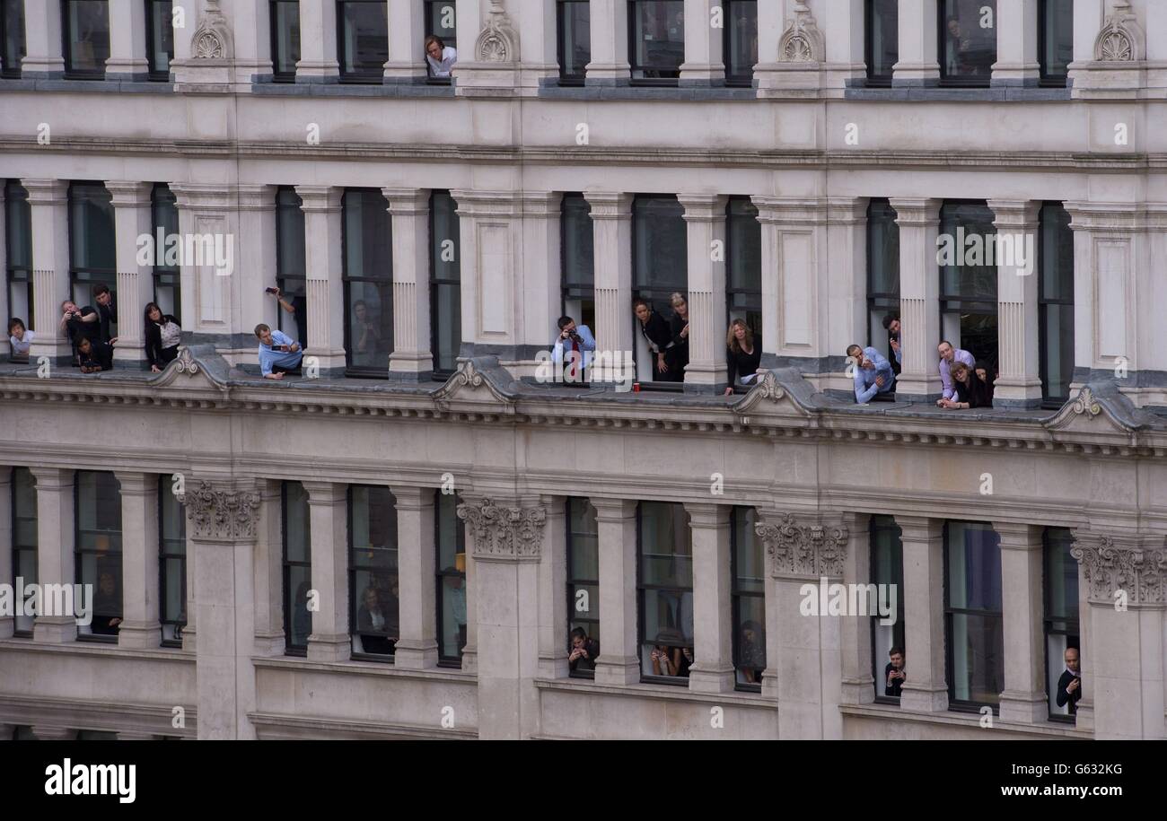 Büroangestellte schauen aus ihren Fenstern, als der Sarg von Baroness Thatcher zur Beerdigung in der St. Paul's Cathedral im Zentrum von London eintrifft. Stockfoto