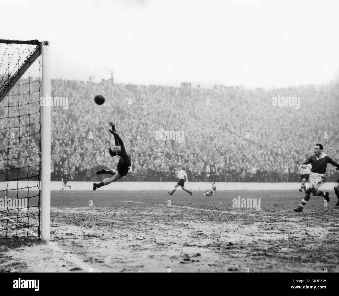 Sunderland-Torhüter Willie Fraser springt in einen kurvigen Sprung, um den Ball zu stoppen, während er ins Netz fliegt, um Charlton Athletic am 29. Dezember 1956 im Spiel der ersten Division in The Valley das zweite Tor zu geben. Stockfoto