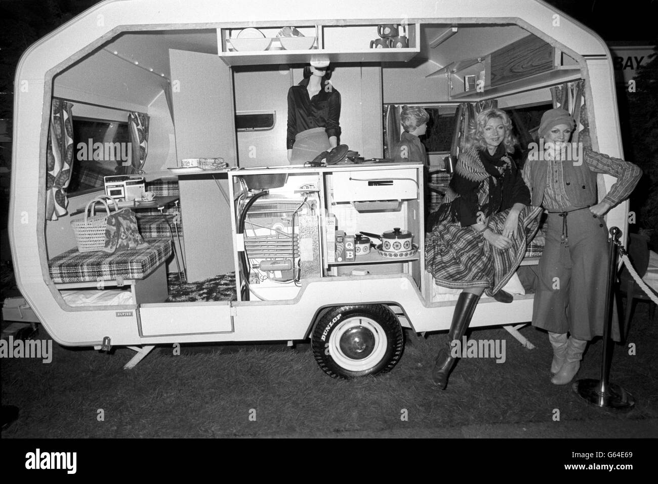Die Modelle Lia (links) und Charlie posieren vor einer Cutaway-Version des Sprite Alpine Caravans, einem kompakten Modell mit 4 Liegeplätzen (12ft 3ins x 6ft 7ins), einem der Exponate, die auf der Caravan Camping Holiday Show im Earls Court ausgestellt werden. Die Show wurde vom Herzog von Gloucester eröffnet. Stockfoto