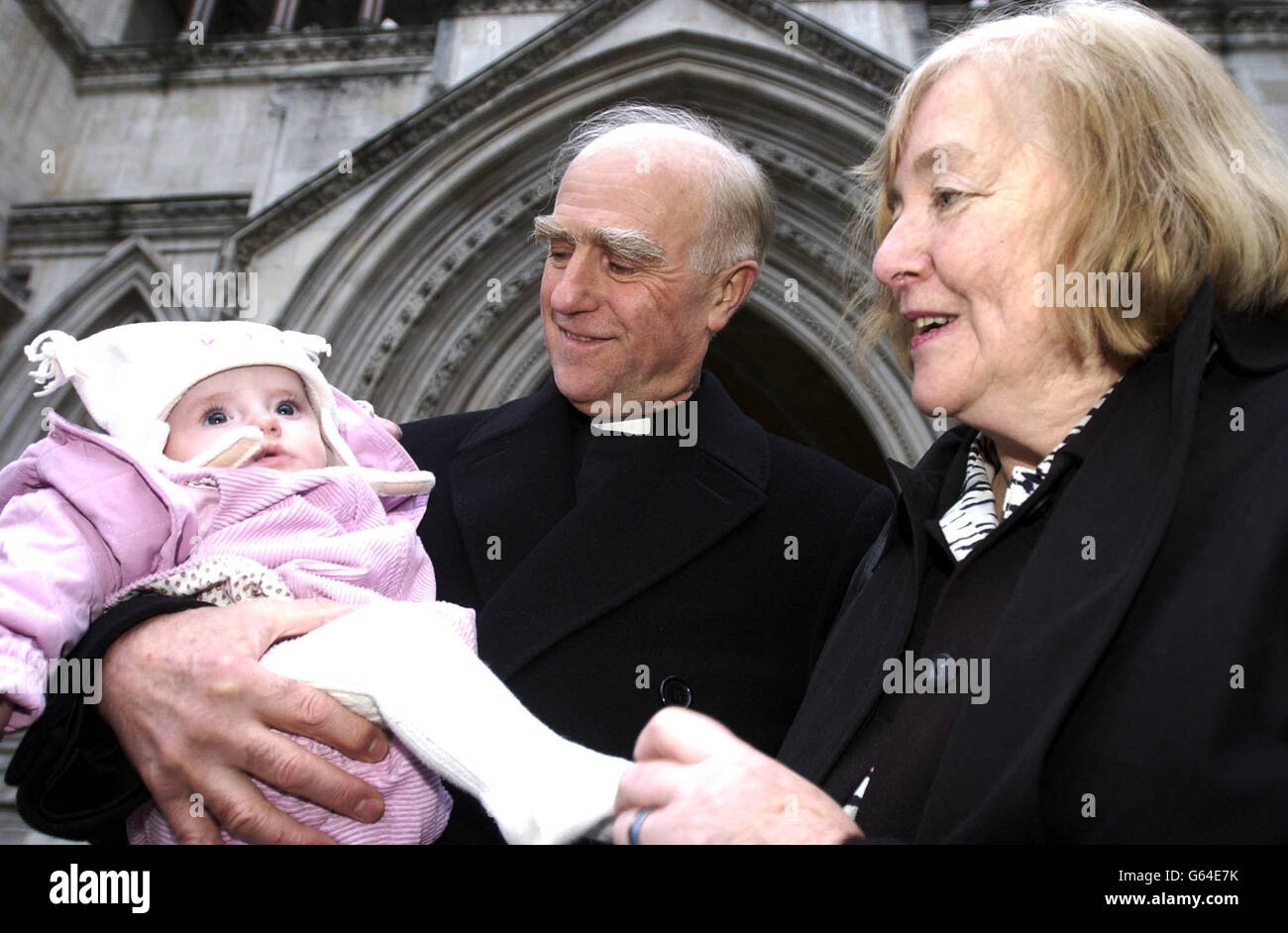 Der Rev. Ray Owens steht vor dem High Court im Zentrum von London, mit Frau Janice und viereinhalb Monate alter Enkelin Ella. * der Pfarrer Owen stimmte einer außergerichtlichen Einigung mit der Kirche zu, nachdem er sich für den Aufenthalt in seinem Pfarrhaus eingesetzt hatte, nachdem er von seinem Posten als "Teamrektor" für Hanley in der Diözese Litchfield in der Nähe von Stoke on Trent entfernt worden war. Rev. Owen schwor, seinen Kampf mit der Hilfe von AMICUS fortzuführen, um das Gesetz zu ändern, um dem Klerus Arbeitsrechte zu geben. Stockfoto