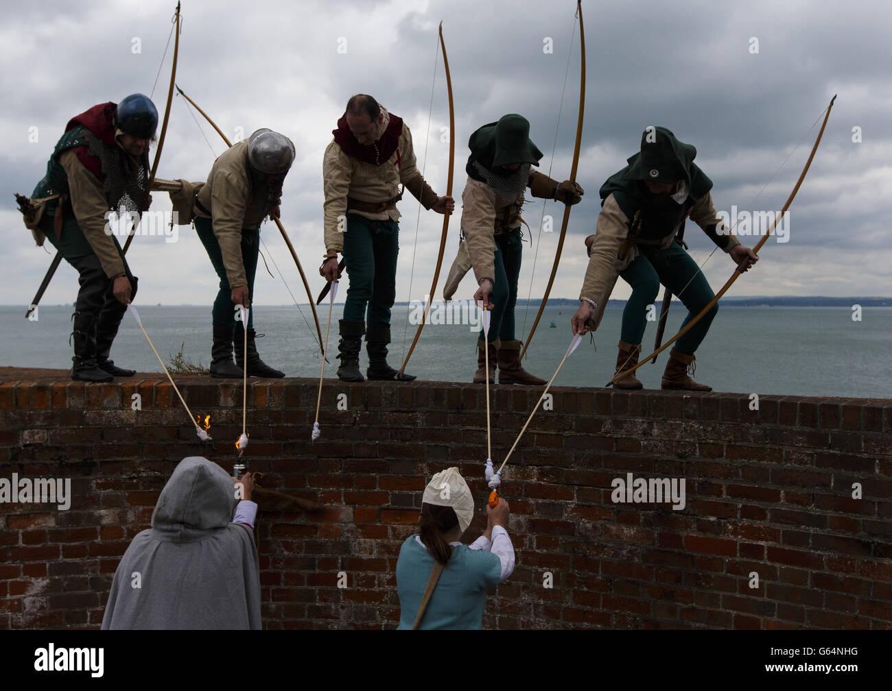 Bogenschützen der Purbrook Bowmen, gekleidet in Tudor-Kleidung, bereiten sich darauf vor, eine voll flammender Pfeile von Southsea Castle in den Solent zu feuern, wo die Mary Rose 1545 sank. Stockfoto