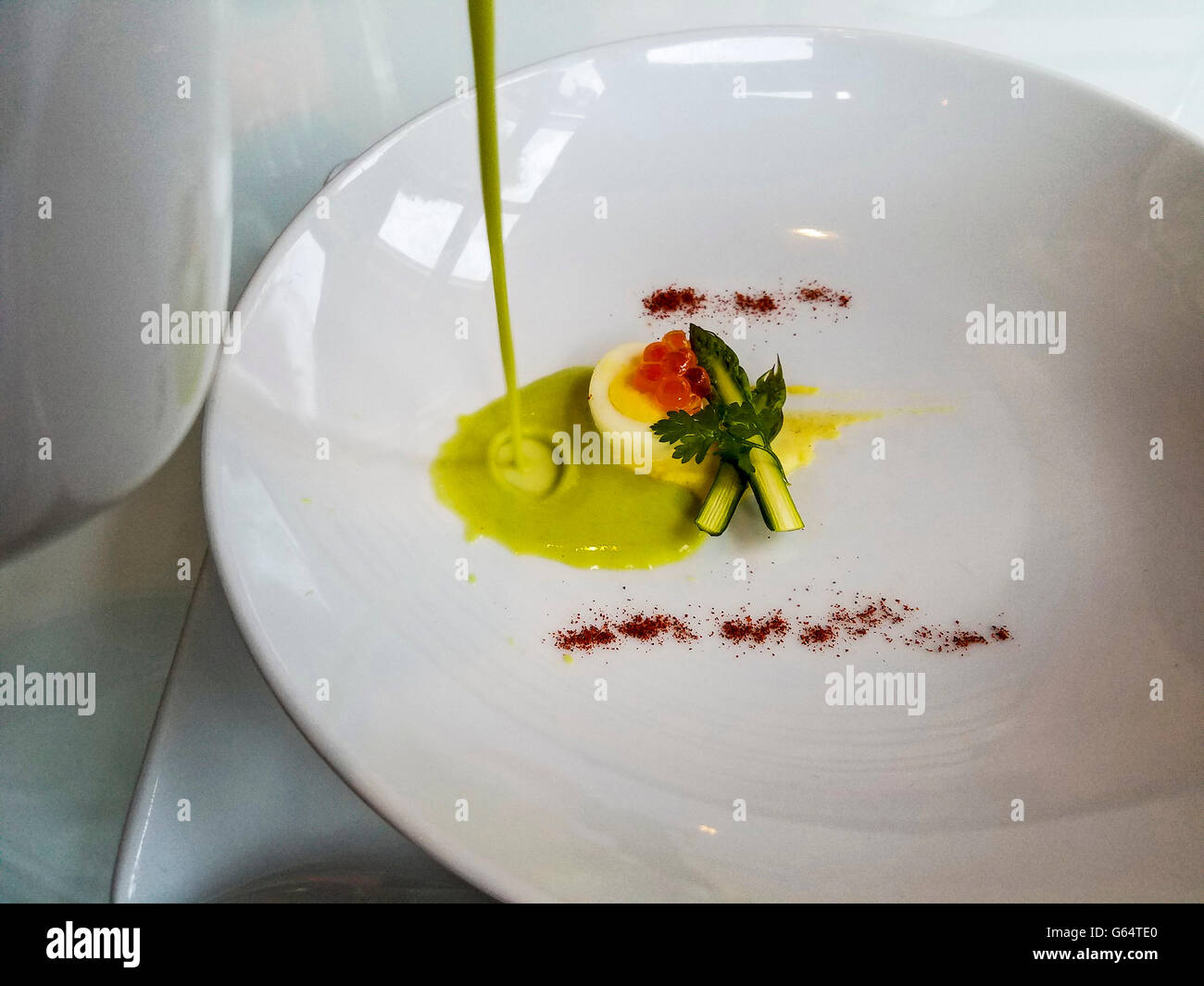 Gießen Spargelsuppe über Wachtelei und Lachsrogen mit winzigen Spargel während Gourmet-Mahlzeit. Stockfoto