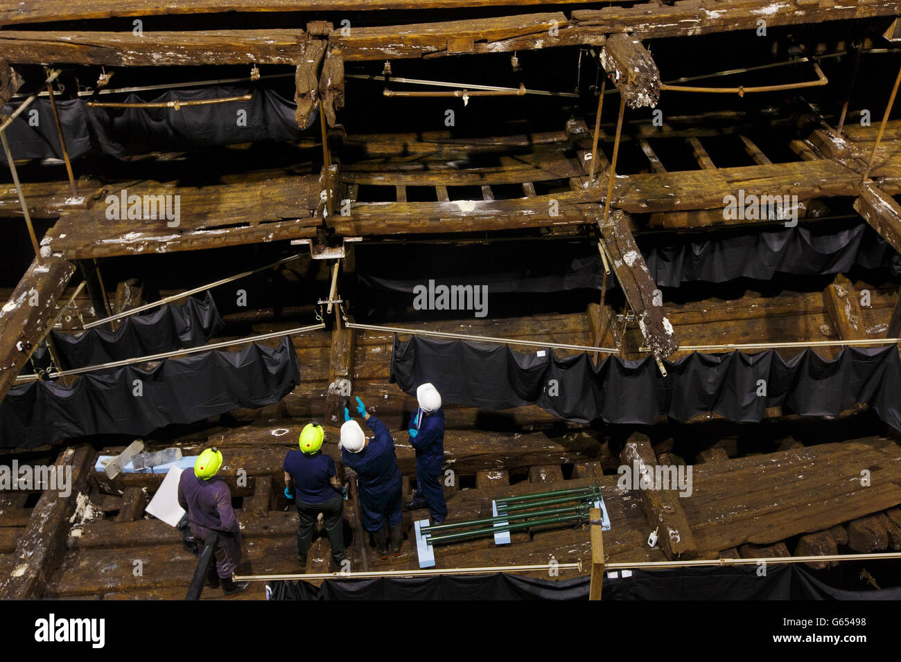 Restauratoren stehen im Inneren des Rumpfes des Tudor-Kriegsschiffs, der Mary Rose, im neuen Mary Rose Museum, das Ende Mai im Portsmouth Historic Dockyard in Hampshire eröffnet wird. Stockfoto