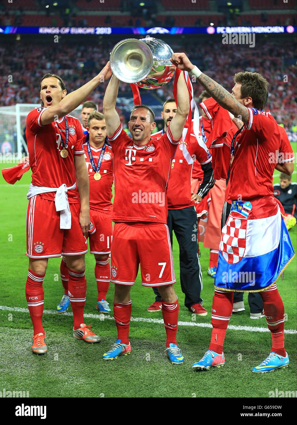 (Von links nach rechts) die Bayern Münchens Daniel van Buyten, Franck Ribery und Mario Mandzukic feiern mit dem Champions-League-Pokal auf dem Platz Stockfoto