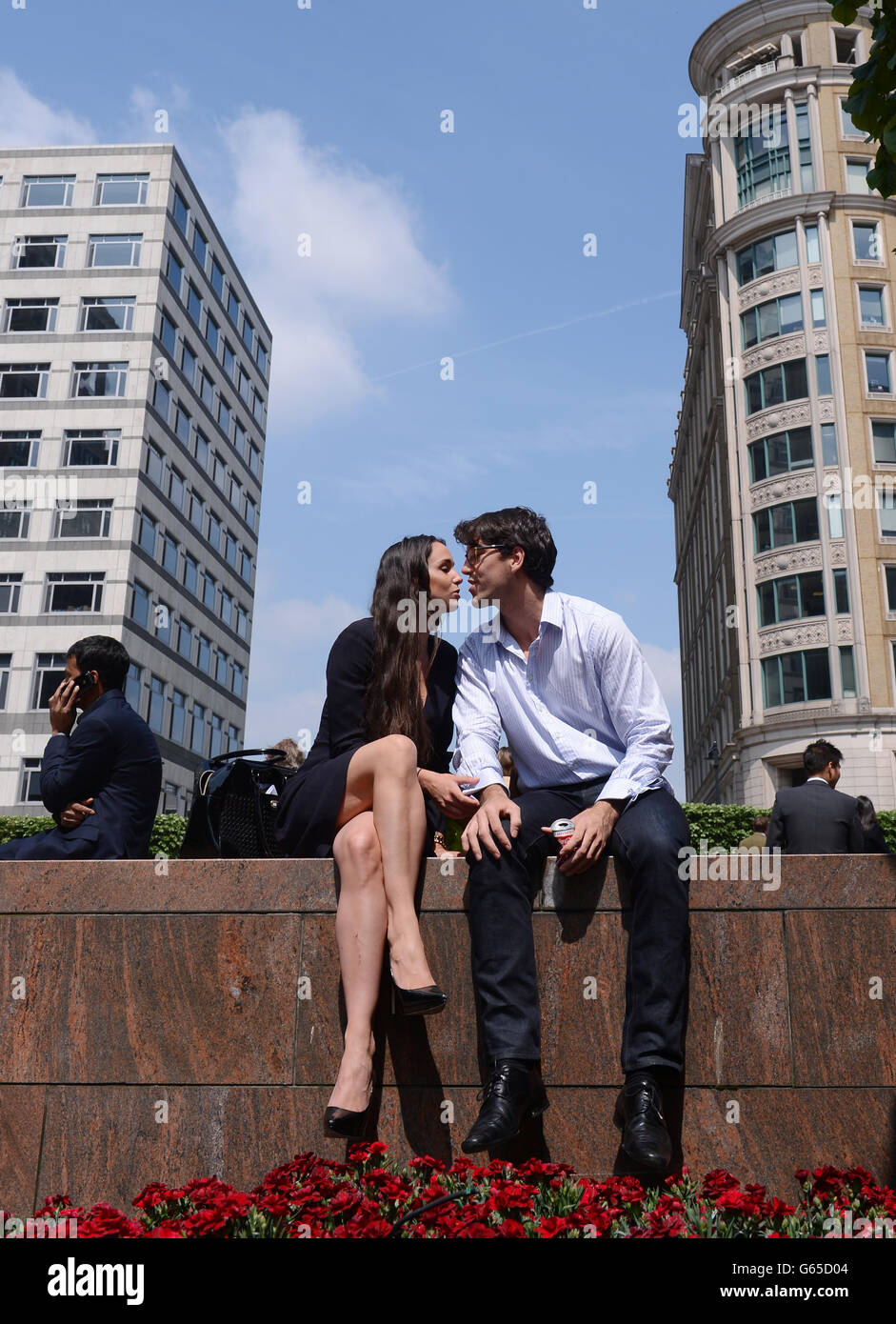 Büroangestellte genießen die Sonne, als die Temperaturen auf 19c in Canary Wharf in London stiegen. Stockfoto