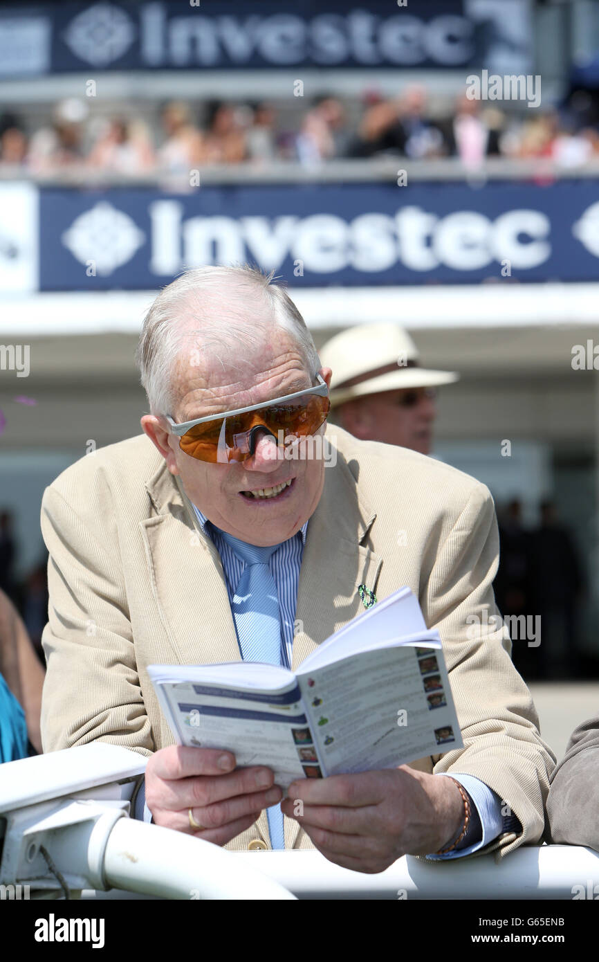Pferderennen - Der Investec Ladies Day - Epsom Downs Racecourse. Ein Rennfahrer schaut auf der Tribüne über seine Rennkarte Stockfoto