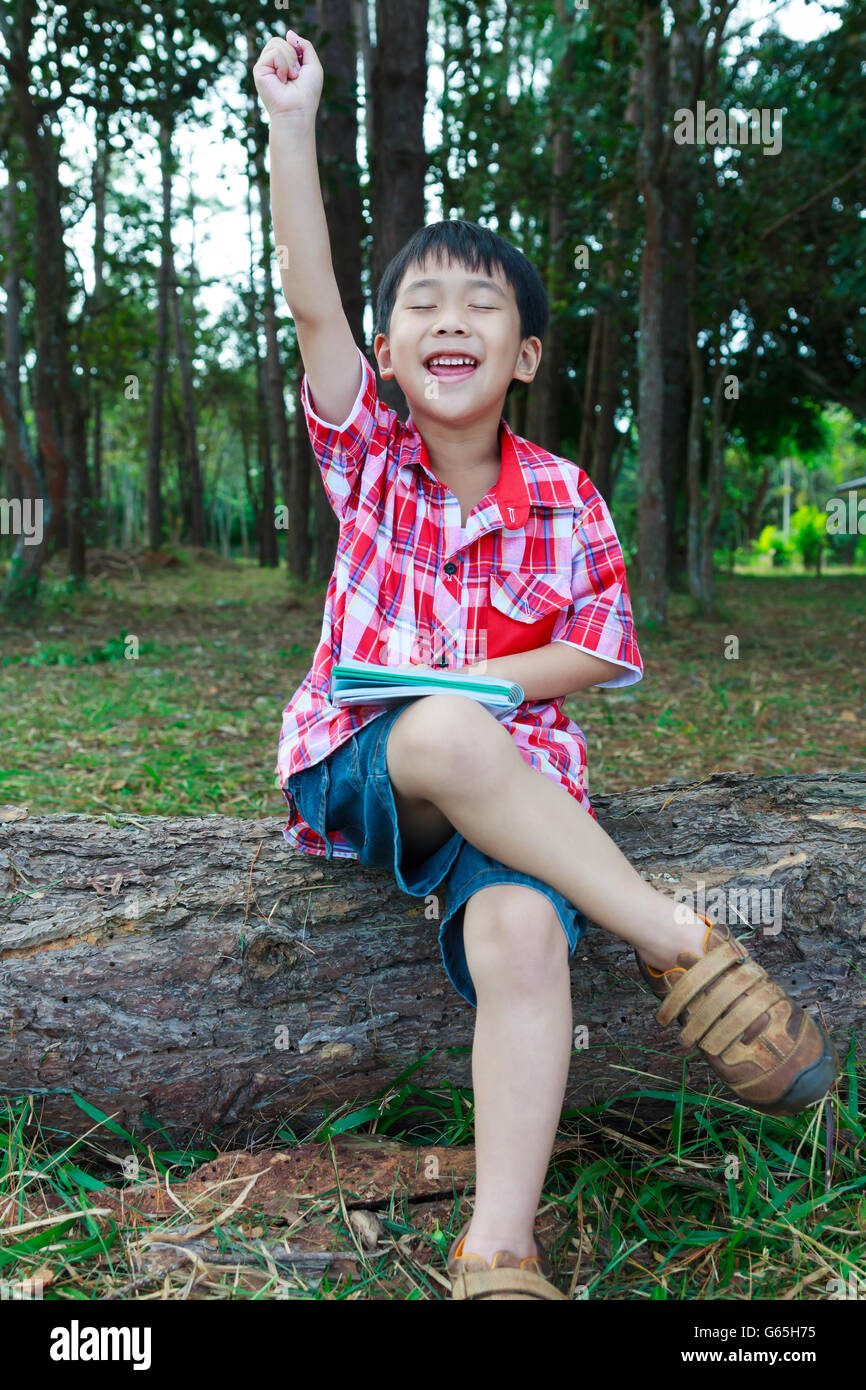 Hübscher Junge asiatische kann Problem beheben. Kind mit den geschlossenen Augen denken. Kind fröhlich auf Holzscheit im Park. Im Freien in der Stockfoto