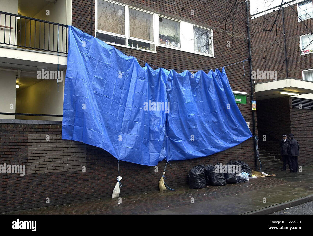 Eine blaue Plane bedeckt einen Wohnblock in Camden, im Norden Londons, während Polizisten Wache halten. Detektive der Mordkommando suchten eine Wohnung in der Nähe, in der zerstückelte Körperteile in Müllsäcken entdeckt wurden. * die Suche folgt der Entdeckung von Überresten durch einen Landstreicher, als er in einer Mülltonne nach Nahrung gesucht hat. Scotland Yard glaubt, dass die Überreste einer Frau und eines jungen Mädchens sind, und die forensischen Tests wurden heute fortgesetzt, um sie zu identifizieren. Es wurden auch Tests an einem anderen Satz von Körperteilen durchgeführt, die in der Nähe entdeckt wurden, um festzustellen, ob sie zu den gleichen Opfern gehören. Stockfoto