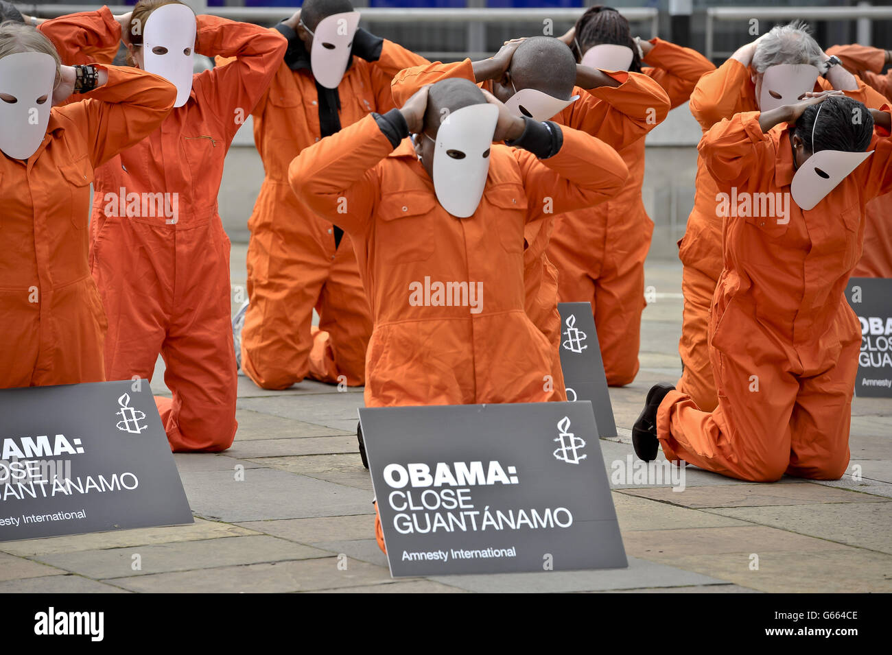 Demonstranten von Amnesty International, die in orangefarbenen Sprunganzügen und Masken gekleidet sind, halten Plakate, auf denen sie fordern, dass Präsident der Vereinigten Staaten, Barack Obama, Guantanamo schließt, während sie sich vor dem G8-Gipfel vor der Waterfront in Belfast versammeln. Stockfoto