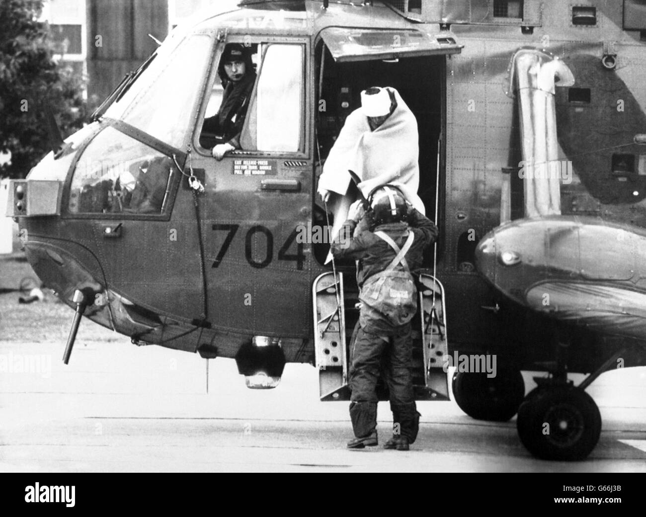 Mit einem verbandten Kopf und einer Decke wird einem Überlebenden der Nordsee-Ölförderplattform Piper Alpha von einem Rettungshubschrauber im Aberdeen Royal Infirmary geholfen. Nach der Katastrophe folgte eine umfangreiche Suche nach Überlebenden, die die Plattform schnell zu einem wütenden Inferno werden sah. Stockfoto