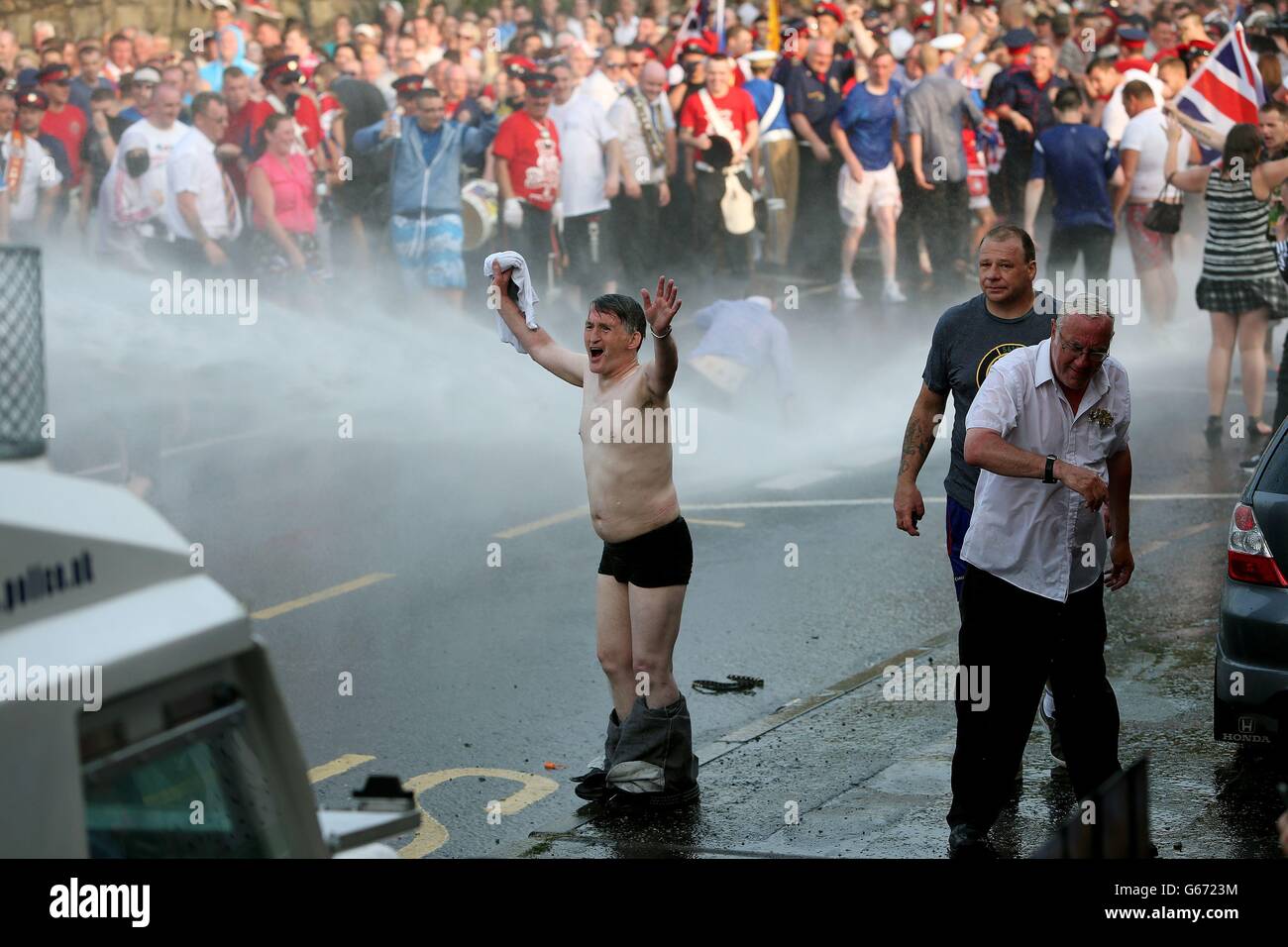 Ein Loyalist konfrontiert die Polizei in Nord-Belfast, nachdem die von der Regierung ernannte Paraden-Kommission beschlossen hatte, Orangemen davon abzuhalten, durch Ardoyne in Nord-Belfast zu gehen, nach einem Tag friedlicher, am zwölften Juli festlicher Ordnungsparaden in Nordirland. Stockfoto