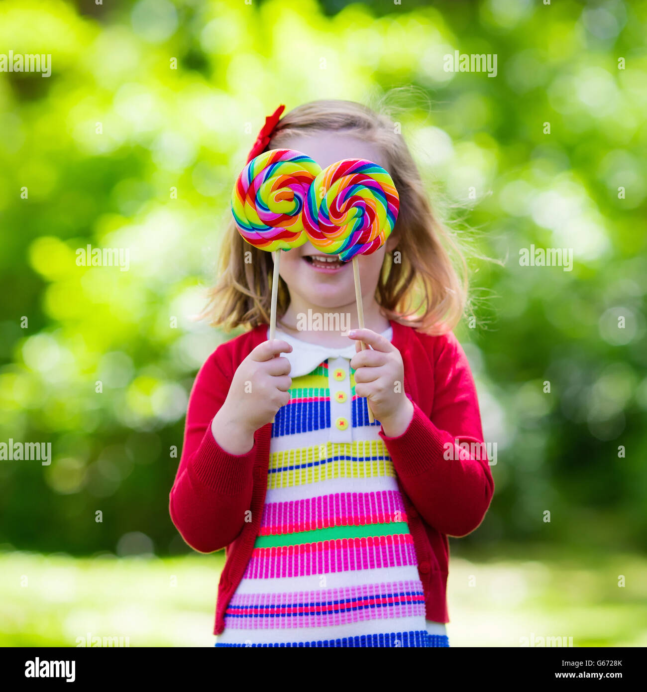 Niedliche kleine Mädchen mit großen bunten Lollipop. Kind, essen Süßigkeiten Bar. Süßigkeiten für kleine Kinder Stockfoto